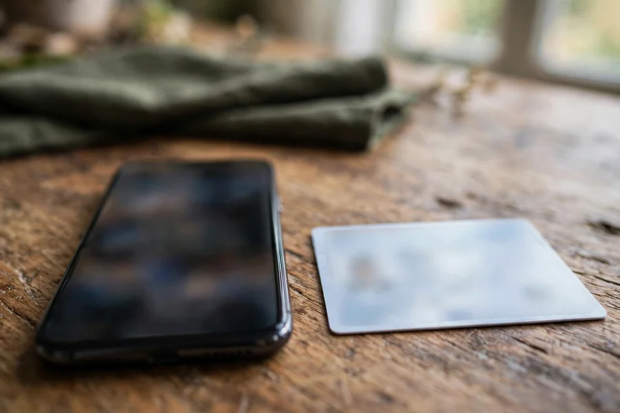 A mobile phone beside an identity card on a table, with all card and screen details blurred