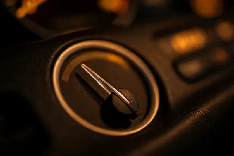 A car dashboard gauge needle near empty at night, face blurred